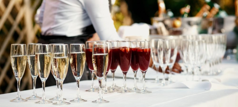 Glasses with red and white wine stand on the white dinner table outside